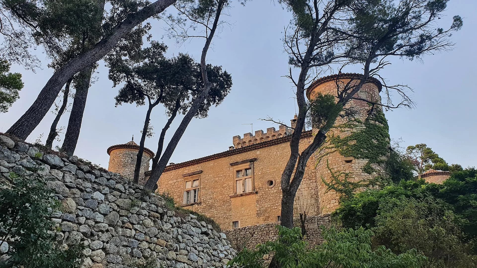 Le château de Montarnaud et ses tours rondes, derrière les pins