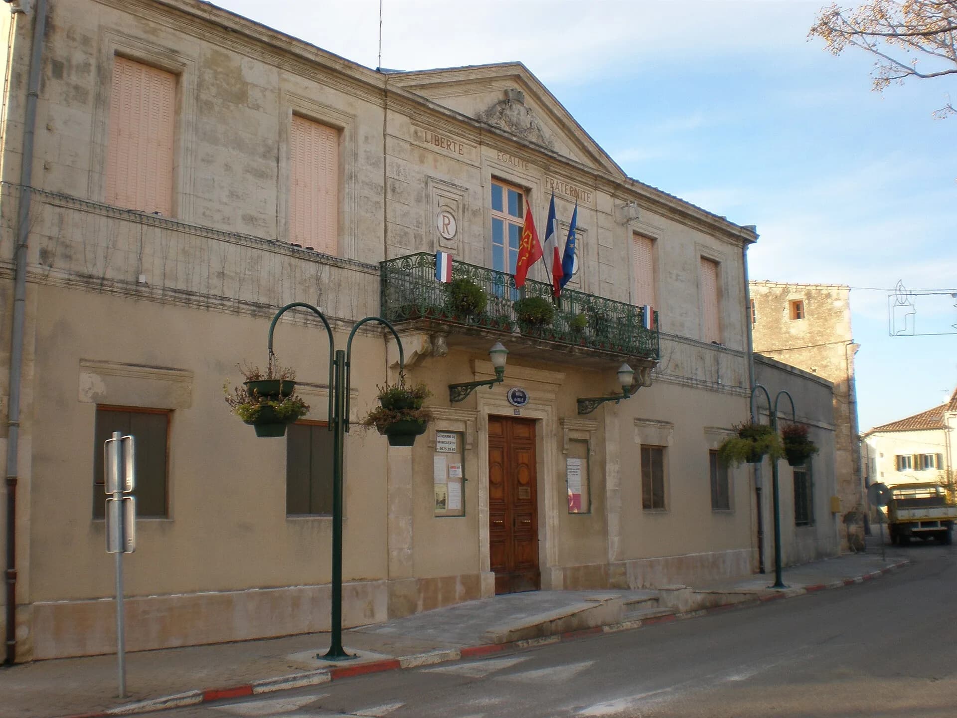 La mairie de Redessan, son balcon en fer forgé et ses paniers fleuris