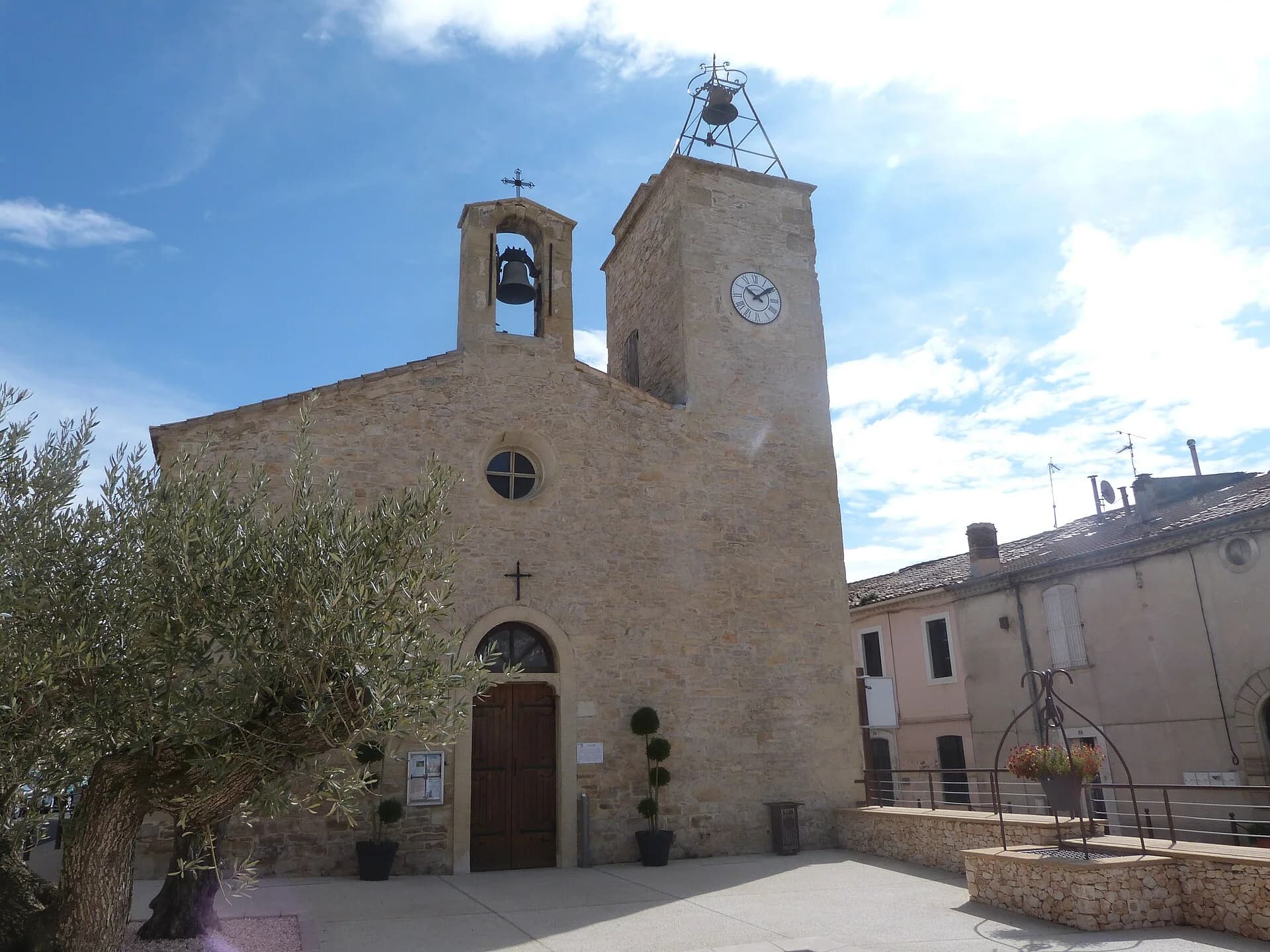 La place de l'Église à Uchaud, son clocher-mur, la tour de l'horloge et les maisons du village