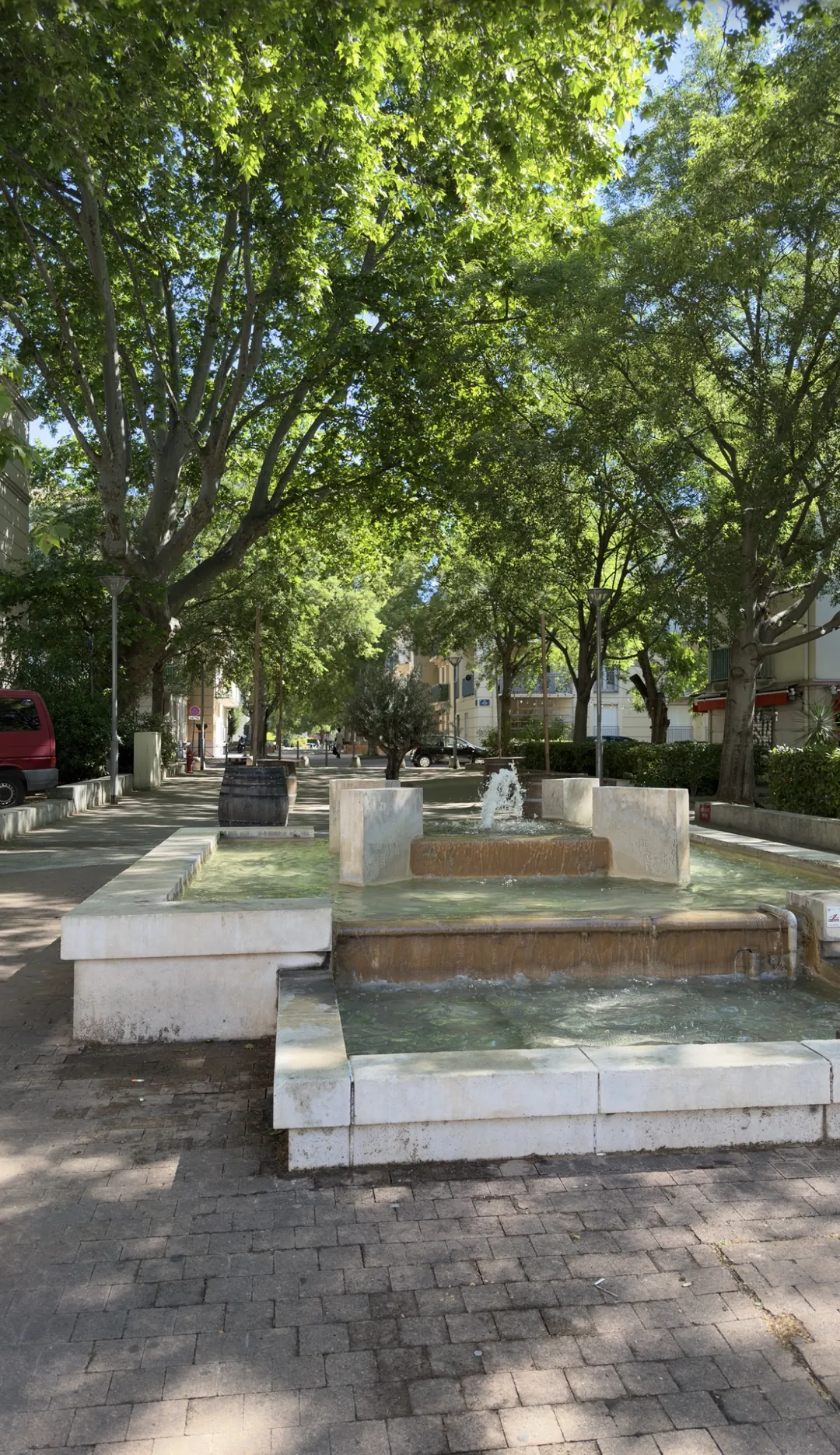 Place ombragée avec fontaine en pierre et platanes centenaires dans le quartier des Beaux-Arts à Montpellier